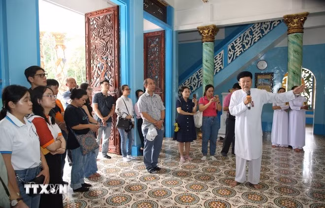 Đoàn du lịch nghe thuyết trình về sự hình thành Tòa Thánh Cao Đài Tây Ninh. Ảnh: Giang Phương/TTXVN