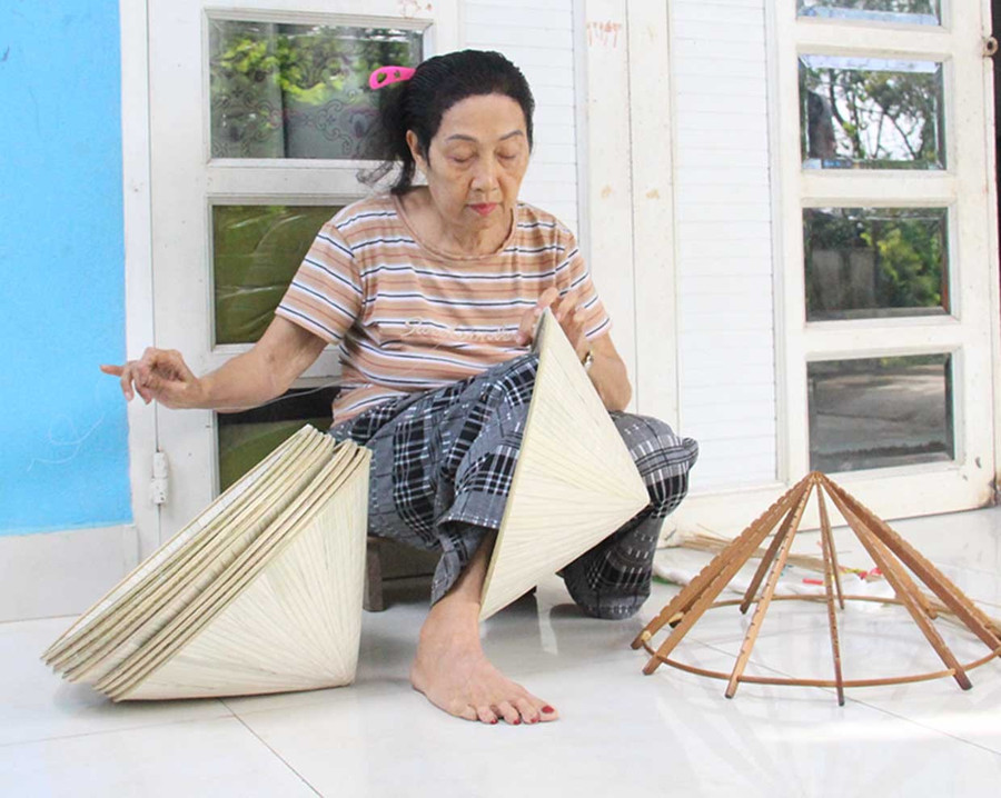 Bà Nguyễn Thị Đúng (tổ dân phố Tiên Hội, phường An Nhơn Bắc) vẫn miệt mài với nghề chằm nón lá. Ảnh: Trọng Lợi