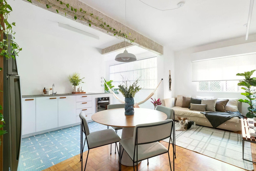 Phòng khách được bài trí theo tinh thần tối giản, ưu tiên sự thoải mái. Sofa màu trung tính, thảm nhẹ và nhiều cây xanh tạo cảm giác thư giãn, gần gũi.