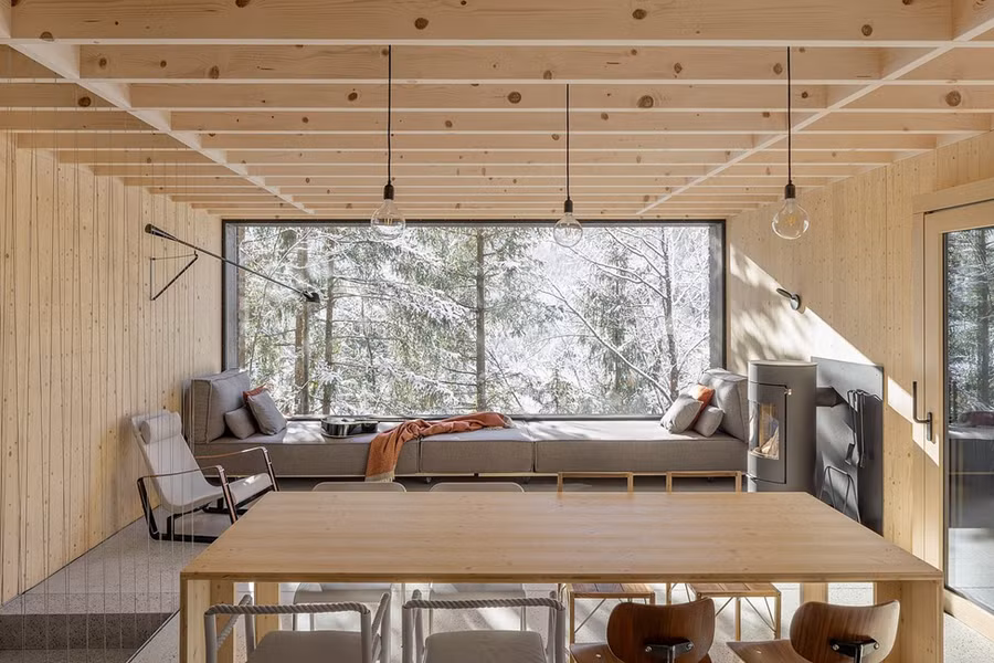 Hình khối kéo dài, tầng trệt bằng đá vững chãi và tầng trên bằng gỗ tối màu, được tô điểm bởi mái nhà nổi bật: kết cấu gỗ lộ thiên, mái hiên nhô rộng và máng xối vượt ra ngoài tường.