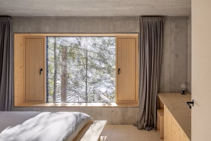 Hiên gỗ bên hông đóng vai trò như một khoảng sân trước và không gian sinh hoạt ngoài trời, kết nối liền mạch giữa nội thất bên trong với cảnh quan xung quanh.