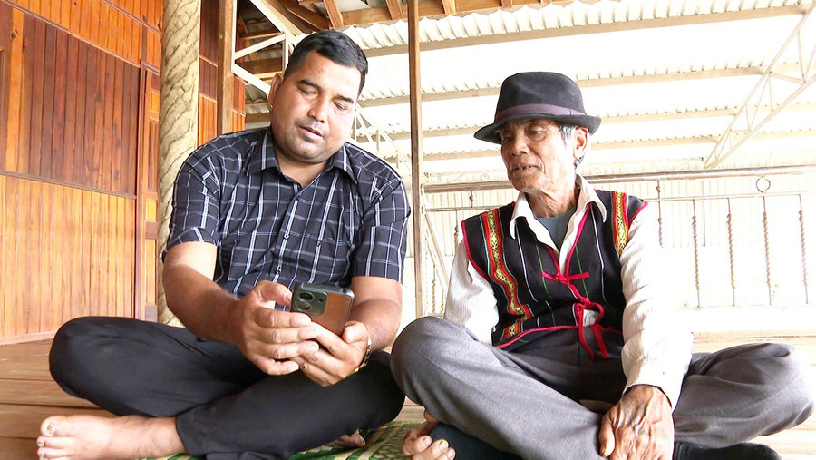 Ông Rơ Châm Gloan (bên trái), Bí thư Chi bộ kiêm Trưởng thôn Al (xã Ia Ly) hướng dẫn đảng viên sử dụng Sổ tay đảng viên điện tử. Ảnh: Minh Lý