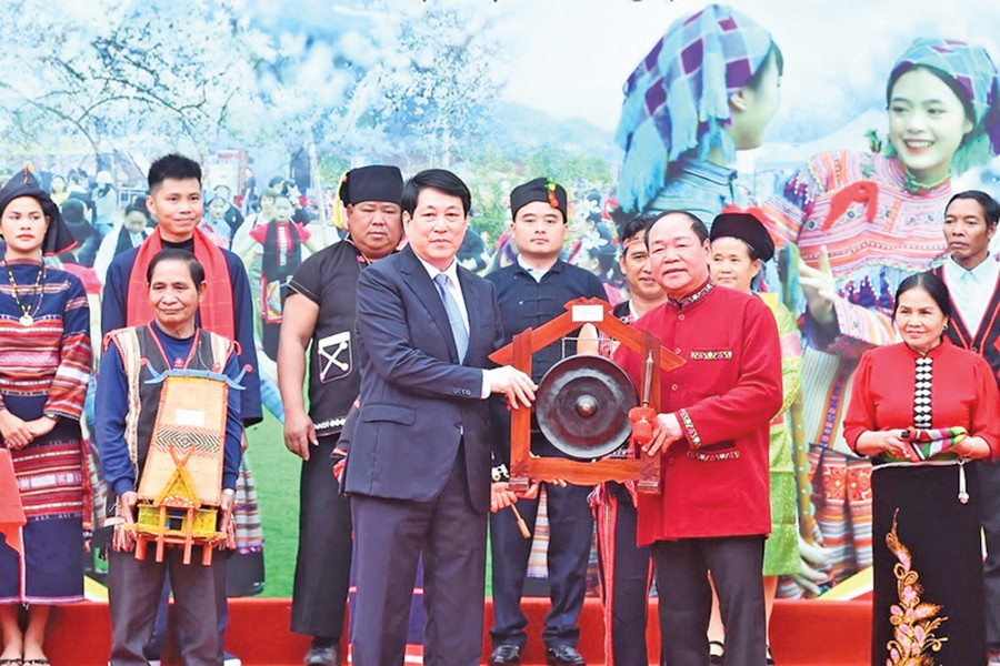 Nghệ nhân người Jrai Nay Brui (hàng trước, đầu tiên từ trái sang) chụp ảnh lưu niệm cùng Chủ tịch nước Lương Cường (hàng trước, đứng giữa) tại Ngày hội “Sắc xuân trên mọi miền Tổ quốc” năm 2025. Ảnh: NVCC