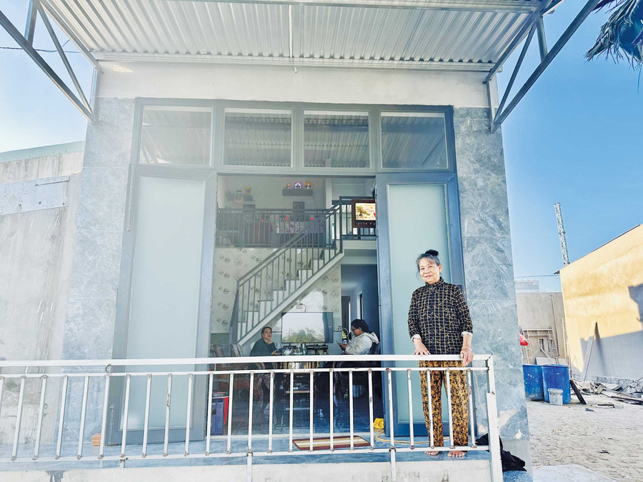 Bà Nguyễn Thị Chưa (thôn Vinh Quang 2, xã Tuy Phước Đông) bên căn nhà mới. Ảnh H.T