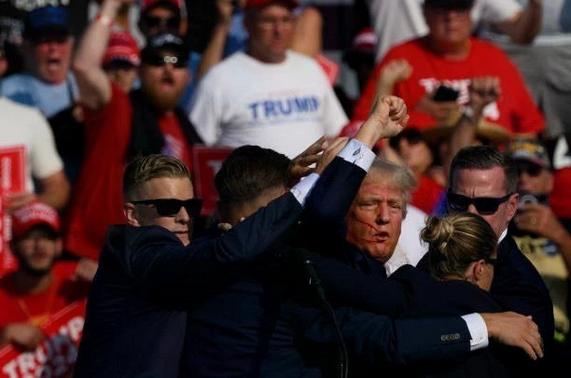 Ông Donald Trump được mật vụ Mỹ hộ tống rời khỏi bục diễn thuyết trong cuộc vận động tranh cử ở thành phố Butler, bang Pennsylvania sau khi xảy ra vụ nổ súng, ngày 13/7/2024. (Ảnh: Getty Images/TTXVN) ddthuong-vien-my.jpg