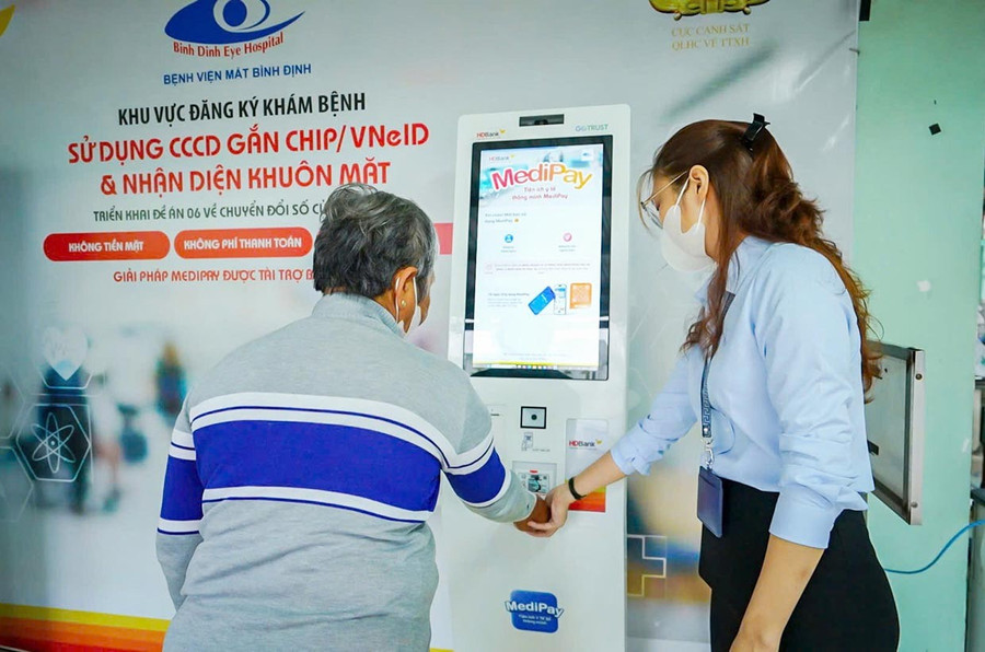 Nhân viên Bệnh viện Mắt Bình Định hướng dẫn người dân thao tác đăng ký khám-chữa bệnh. Ảnh: Dũng Nhân 22trong-loi.jpg