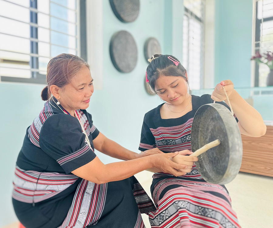 Bà Đinh Thị Tuyết (trái) hướng dẫn em Đinh Thị Kim Ngân cách đánh chinh tía (chiêng 5). Ảnh: D.Đ Bà Đinh Thị Tuyết (bìa trái) hướng dẫn em Đinh Thị Kim Ngân cách đánh chinh tía (chiêng 5).