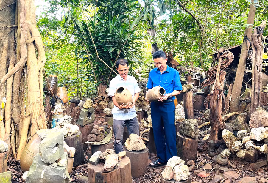 Ông Nguyễn Văn Hưng (bên trái) giới thiệu với công chức Phòng Văn hóa - Xã hội xã Chư Prông về cặp ché vợ chồng. Ảnh: P.D