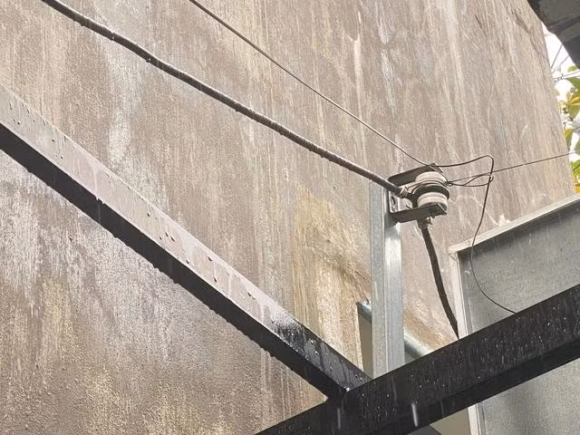 Một đường dây điện được gắn trên trụ kim loại dẫn vào nhà dân.