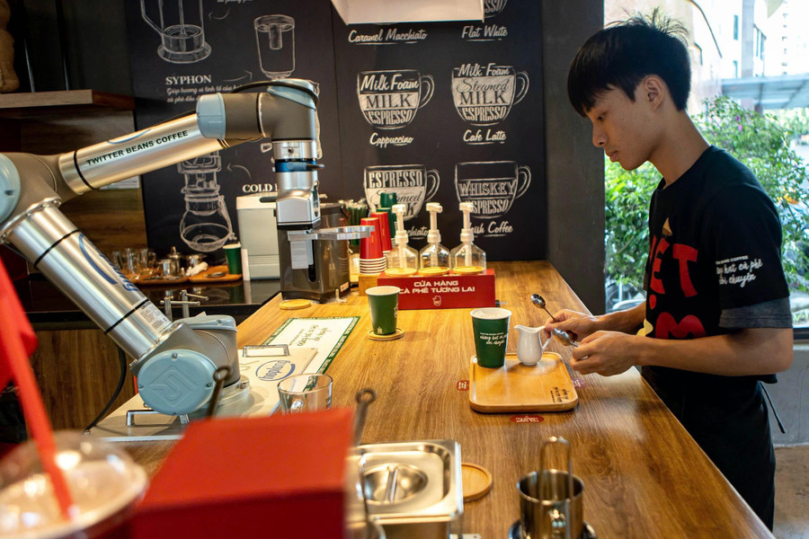 Tại quầy pha chế, nhân viên sắp xếp các loại cốc, sữa, cà phê để cánh tay cơ khí của robot thao tác dễ dàng. ẢNH: MINH NHÂN Tại quầy pha chế, nhân viên sắp xếp các loại cốc, sữa, cà phê để cánh tay cơ khí của robot thao tác dễ dàng. ẢNH: MINH NHÂN