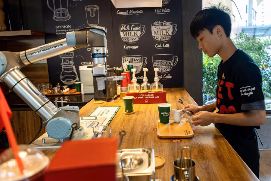 Tại quầy pha chế, nhân viên sắp xếp các loại cốc, sữa, cà phê để cánh tay cơ khí của robot thao tác dễ dàng. ẢNH: MINH NHÂN