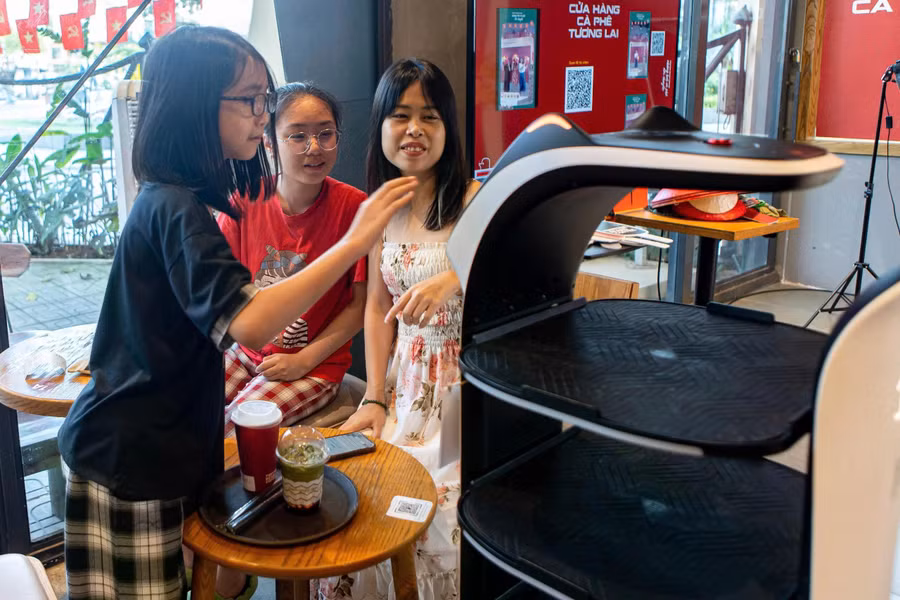 3 mẹ con chị Hà Linh thích thú trải nghiệm robot phục vụ đưa đồ uống đến tận bàn. ẢNH: MINH NHÂN