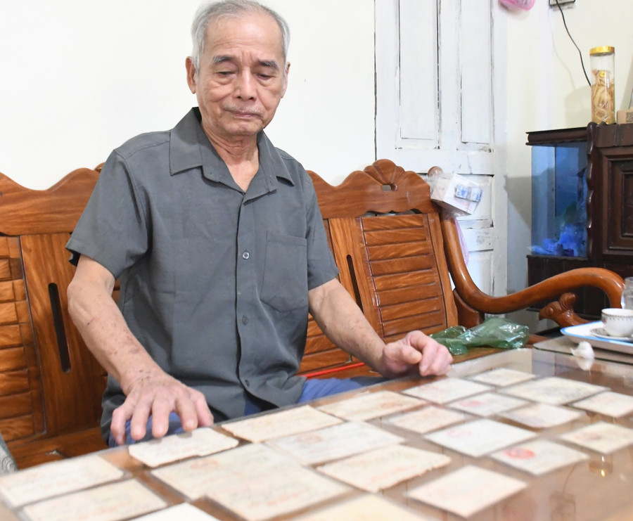 Ông Minh và bộ sưu tập hàng chục giấy xác nhận “Dũng sĩ diệt Mỹ”, “Dũng sĩ quyết thắng”. Ảnh: N.BÌNH 2nguoilinh.jpg