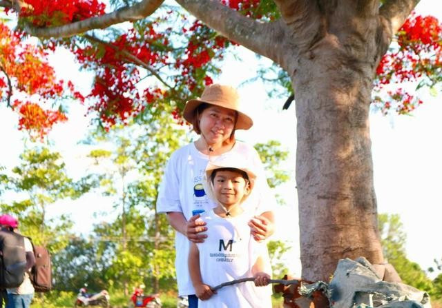 Chị Thùy Dung đưa con trai đến check-in với cây phượng đang gây sốt. ẢNH: THẢO PHƯƠNG Chị Thùy Dung đưa con trai đến check-in với cây phượng đang gây sốt. ẢNH: THẢO PHƯƠNG