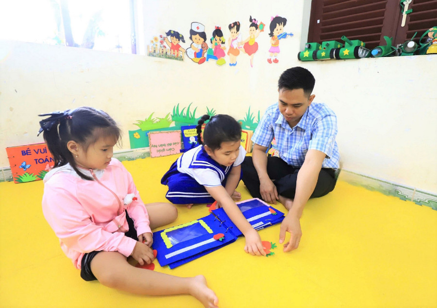 Thầy giáo Cao Văn Truyền học và chơi cùng các con. Ảnh: DN 2truongsa.jpg