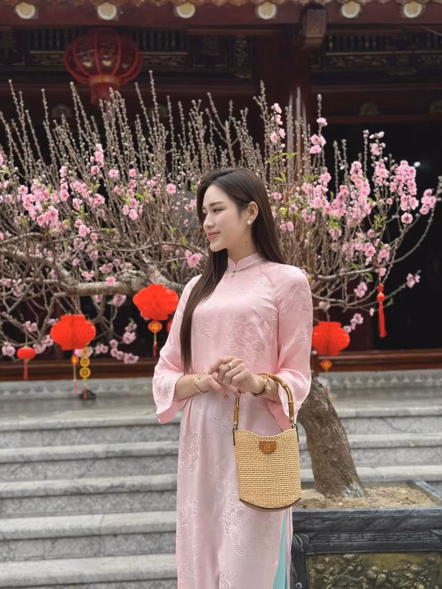 Hoa hậu Việt Nam 2020 chọn áo dài tông màu hồng nhạt nữ tính, để tóc thẳng tự nhiên. Cô khéo léo phối cùng chiếc túi cói, trang điểm nhẹ nhàng.