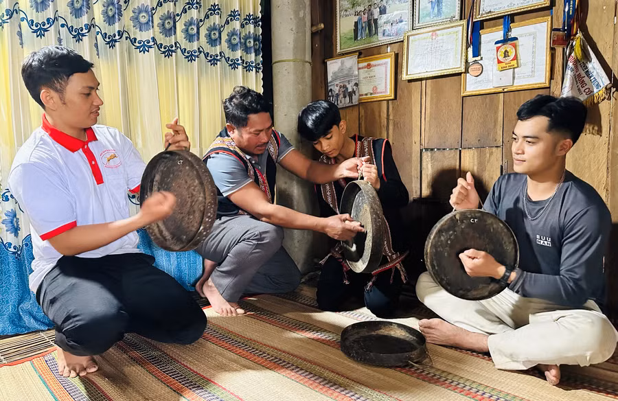 Nghệ nhân Thanh Văn Huấn (thứ hai từ trái sang) cầm tay hướng dẫn cho thanh thiếu niên trong làng cách đánh các bài chiêng. Ảnh: P.C.H