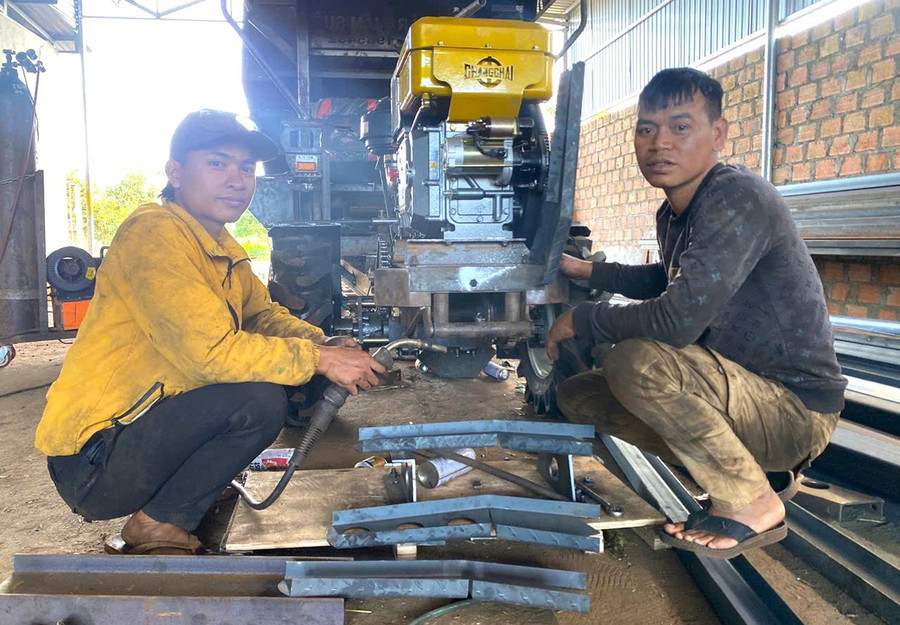 Anh Rchâm Suê (bên phải) hướng dẫn anh Puih Vin sửa chữa xe công nông. Ảnh: R’Ô HOK