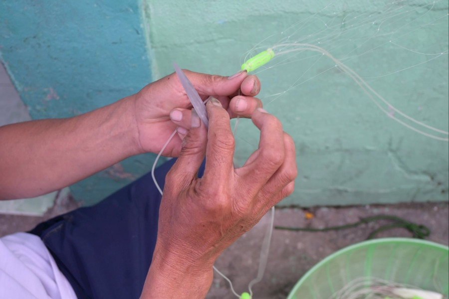 Đôi tay ấy thoăn thoắt ghim, siết, gút… từng mắt lưới mỏng manh, nhanh và chuẩn xác.