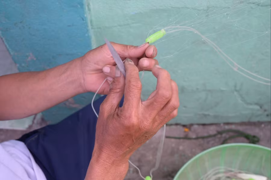 Đôi tay ấy thoăn thoắt ghim, siết, gút… từng mắt lưới mỏng manh, nhanh và chuẩn xác.