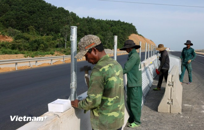 Công nhân triển khai lắp đặt lưới chống chói và dải phân cách một dự án đường bộ cao tốc Bắc-Nam phía Đông. (Ảnh: Khánh Hùng/Vietnam+)