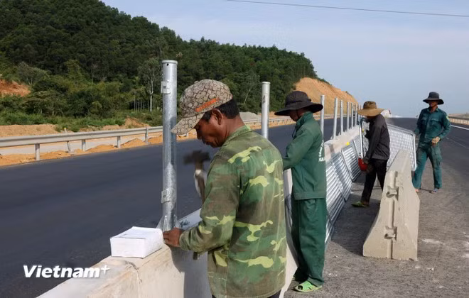 Công nhân triển khai lắp đặt lưới chống chói và dải phân cách một dự án đường bộ cao tốc Bắc-Nam phía Đông. (Ảnh: Khánh Hùng/Vietnam+)