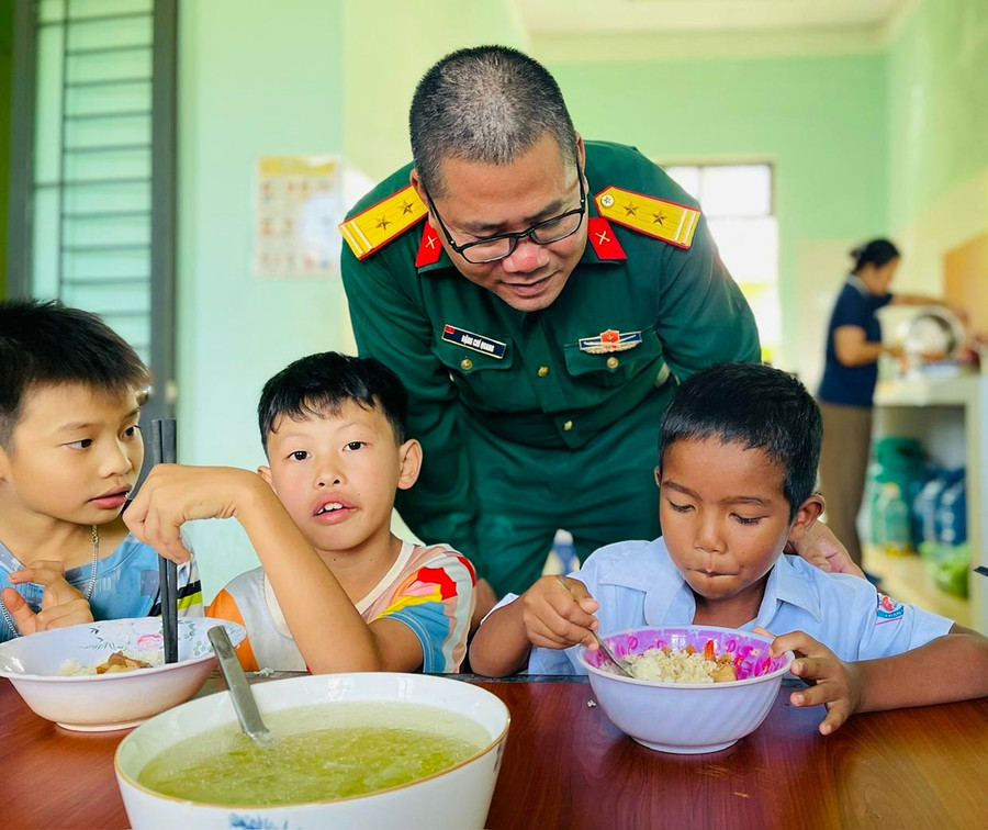 Cán bộ Đoàn Kinh tế - Quốc phòng 710 quan tâm thăm hỏi bữa ăn của các em tại điểm nội trú xã Ia Boòng. Ảnh: P.D
