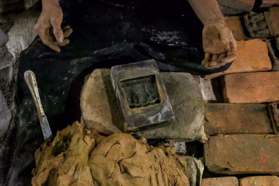 Đất sét được bỏ vào khuôn gỗ, nện chặt để làm tượng Táo quân. ẢNH: LÊ HOÀI NHÂN