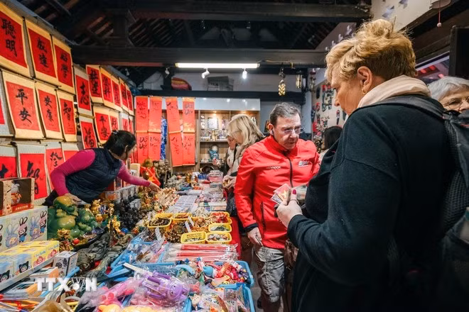 Khách nước ngoài tìm mua những món đồ lưu niệm khi tới thăm Thủ đô Hà Nội. (Ảnh: Phạm Tuấn Anh/TTXVN)