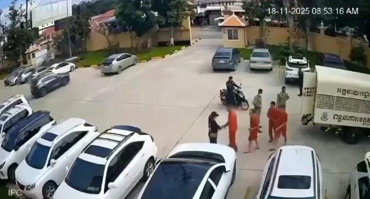 Hình ảnh lại cảnh một phụ nữ đội mũ lưỡi trai đứng chờ tại bãi xe tòa án và bí mật trao súng cho nhóm phạm nhân khi họ vừa bước xuống xe. (Ảnh: Khmer Times)