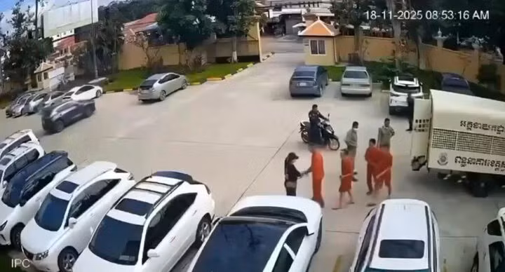 Hình ảnh lại cảnh một phụ nữ đội mũ lưỡi trai đứng chờ tại bãi xe tòa án và bí mật trao súng cho nhóm phạm nhân khi họ vừa bước xuống xe. (Ảnh: Khmer Times)