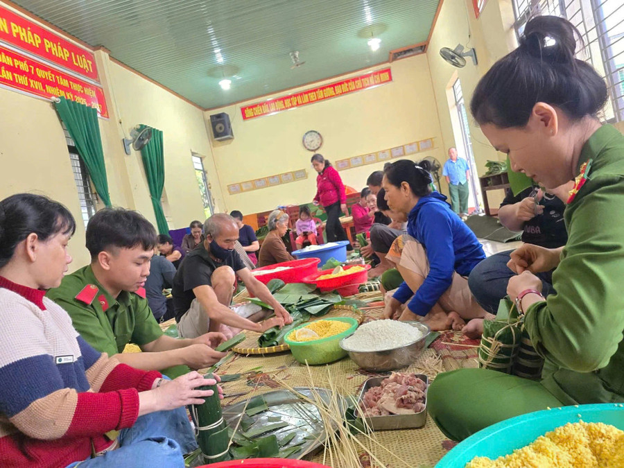 Người dân cùng lực lượng công an gói bánh để gửi những người mắc kẹt trong lũ dữ.