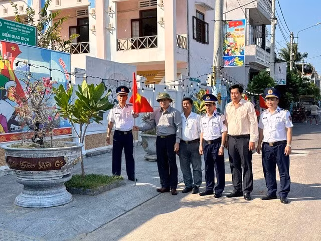 Ông Đặng Hoài Tân (thứ hai từ trái sang) chụp ảnh kỷ niệm trong lễ khánh thành Đường cờ Tổ quốc do Báo Người Lao Động triển khai tại xã Nhơn Hải, TP Quy Nhơn