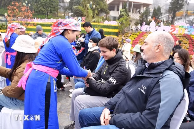 Sa Pa đã tổ chức Lễ đón đoàn khách du lịch đầu tiên gồm 50 du khách trong và ngoài nước đặt chân đến Khu Du lịch quốc gia “xông đất” năm 2025 và thực hiện nghi thức buộc chỉ cổ tay cho du khách với lời chúc may mắn, bình an trong năm mới. (Ảnh: TTXVN phát)