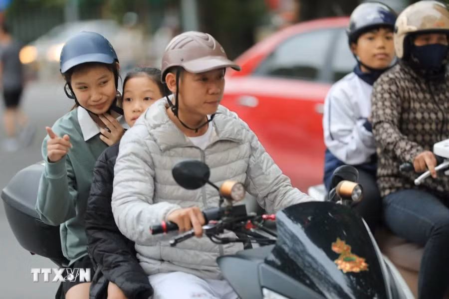 Người dân đã bắt đầu phải mặc thêm áo ấm khi di chuyển trên đường. (Ảnh: Thanh Tùng/TTXVN)