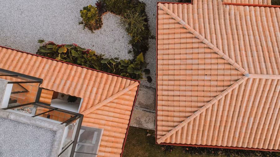 Hai khối nhà được liên kết một cách tinh tế qua hệ mái ngói đất nung đồng điệu, với hai hiên nhà kéo dài nhưng không chạm vào nhau, tạo nên một khoảng mở nhỏ - biểu tượng cho sự chuyển giao công năng.