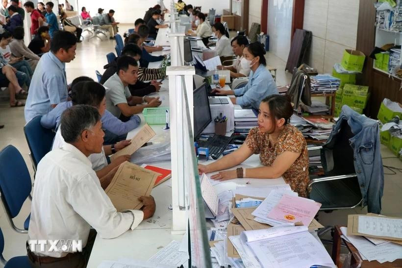 Người dân đến làm thủ tục tại bộ phận “một cửa” UBND huyện Hòa Vang, thành phố Đà Nẵng. Ảnh: Quốc Dũng/TTXVN hop-nhat.jpg