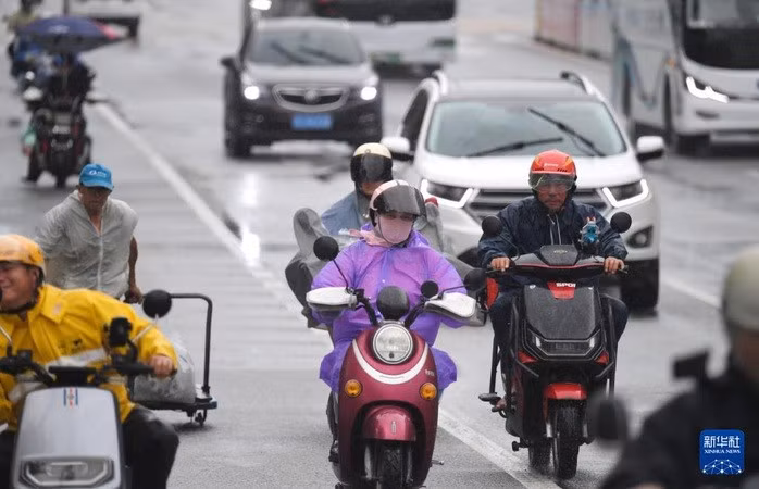 Người dân di chuyển dưới trời mưa ở TP Tam Á, cực Nam của đảo Hải Nam, ngày 12-6. Ảnh: Tân Hoa xã