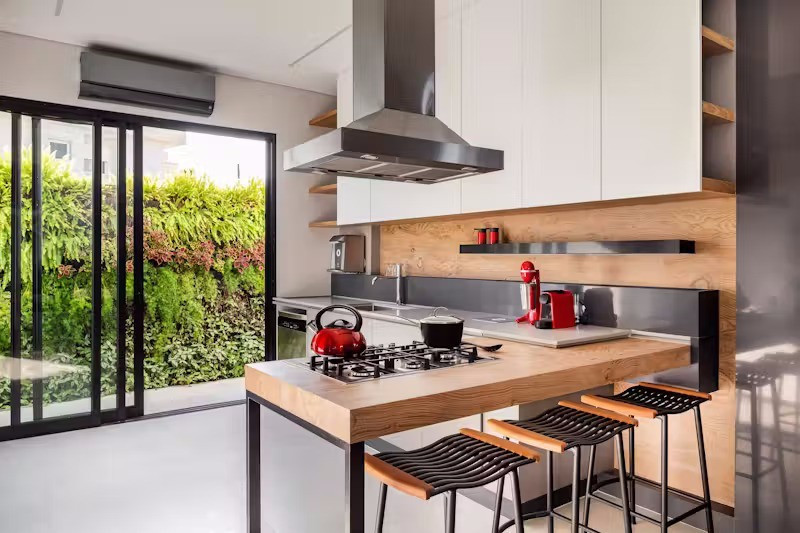 Ở tầng trệt, các khu vực chức năng đều hiện ra trong tầm mắt, đặc biệt là khu bếp được thiết kế như &quot;trái tim&quot; của ngôi nhà. Tại đây, một khung cửa mở phía sau giúp không gian này đóng vai trò cầu nối linh hoạt giữa nội thất và khu vực ngoài trời. Một điểm thú vị khác là việc sử dụng các cánh cửa ẩn được tích hợp cùng tấm ốp gỗ tạo nên vẻ tối giản, tinh gọn.