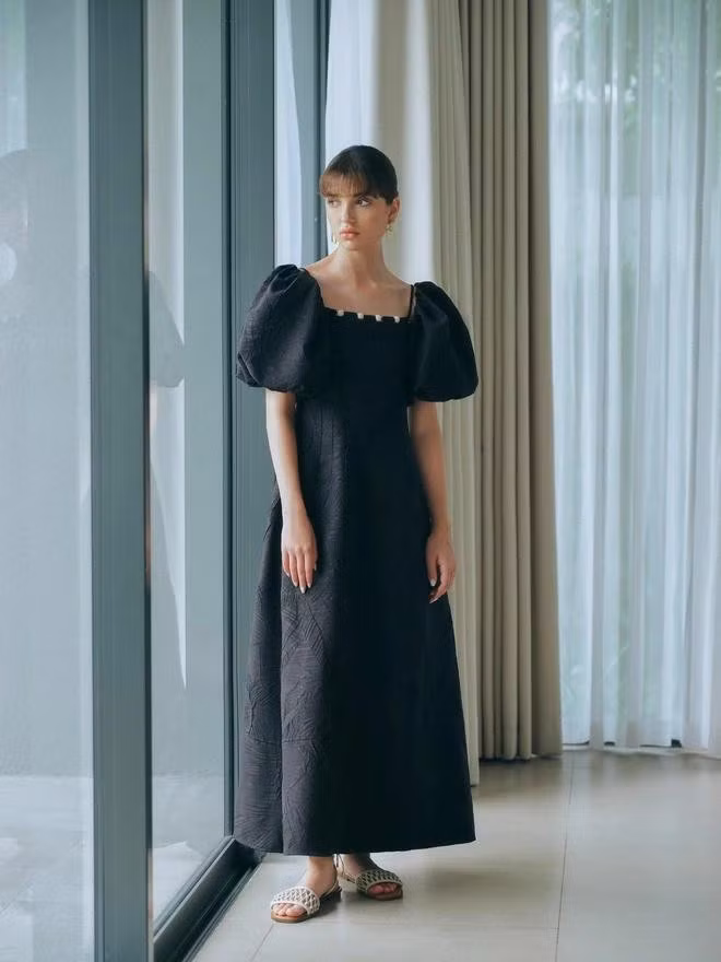 Dáng váy maxi suông nhẹ theo vóc dáng tự nhiên của cơ thể. Chất vải dày vừa phải, đứng phom góp phần thêm vào việc tạo hình ảnh lịch thiệp cho quý cô. Thiết kế cân bằng được vẻ đẹp nữ tính qua chi tiết tay phồng và đường viền cổ vuông đồng thời vẫn phản ánh đậm nét khí chất và phong thái của quý cô sành điệu. ẢNH: RANDOMLIST