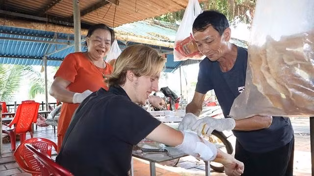 Hai vợ chồng bà Kim giúp Niko băng bó vết thương. ẢNH: Hoàng Giáp