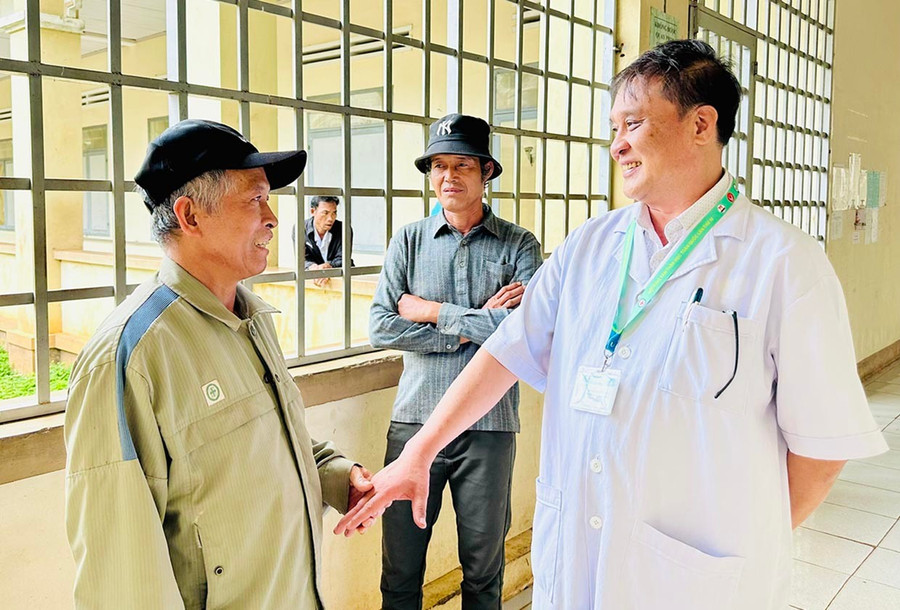Ông Nguyễn Ngọc Hùng (bên trái) trao đổi với bác sĩ Đồng Vĩnh Thanh về tình hình sức khỏe của người thân. Ảnh: Như Nguyện 1nn.jpg