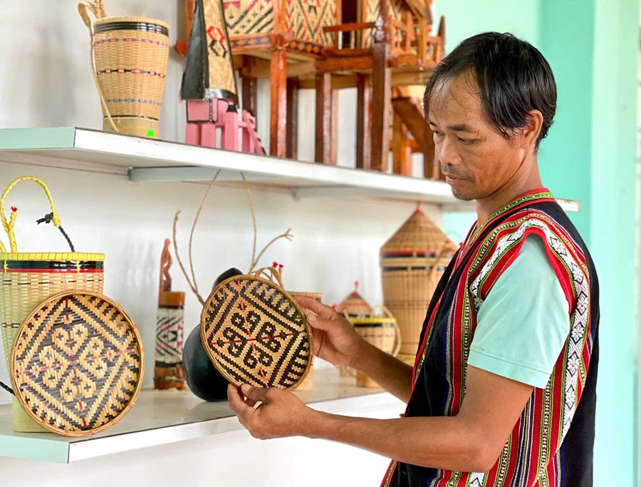 Nghệ nhân Rinh (làng Ngơm Thung, xã Ia Băng) đan các sản phẩm gùi và quà lưu niệm. Ảnh: Vũ Thảo