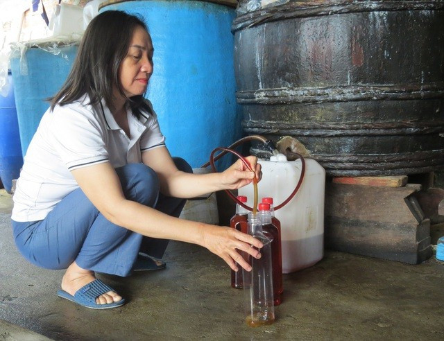 Bà Lê Thị Thùy Trang lấy mắm nhĩ từ thùng gỗ. ẢNH: TRANG THY