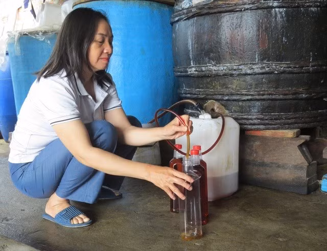 Bà Lê Thị Thùy Trang lấy mắm nhĩ từ thùng gỗ. ẢNH: TRANG THY