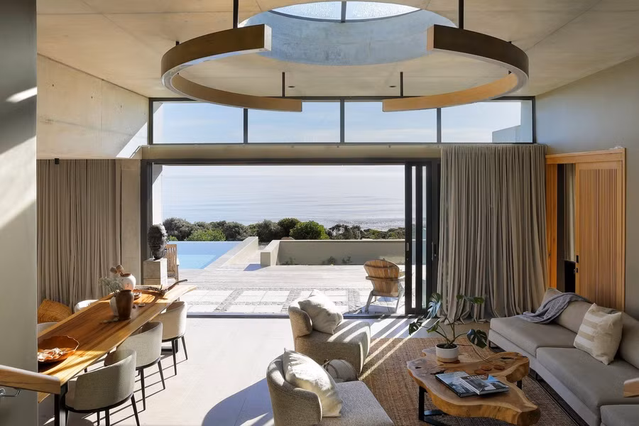 Ngay từ lối vào, tiền sảnh cao hai tầng với những ô cửa kính kịch trần tạo cảm giác rộng mở, dẫn ánh nhìn trực tiếp ra đường chân trời của đại dương bao la. Điểm nhấn tại đây chính là giếng trời hình tròn kết hợp với đèn thả trang trí, không chỉ kết nối các khu vực sinh hoạt mở mà còn nhấn mạnh sự giao thoa giữa ánh sáng và chất liệu, nâng cao giá trị thẩm mỹ và cảm giác ấm cúng cho không gian.