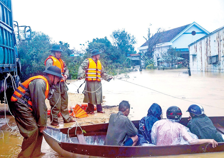 Bí thư Tỉnh ủy Thái Đại Ngọc (người đầu tiên đứng kéo dây) trực tiếp tham gia ứng cứu người dân phường Quy Nhơn Bắc bị cô lập do mưa lũ cuối tháng 11-2025. Ảnh: H.P