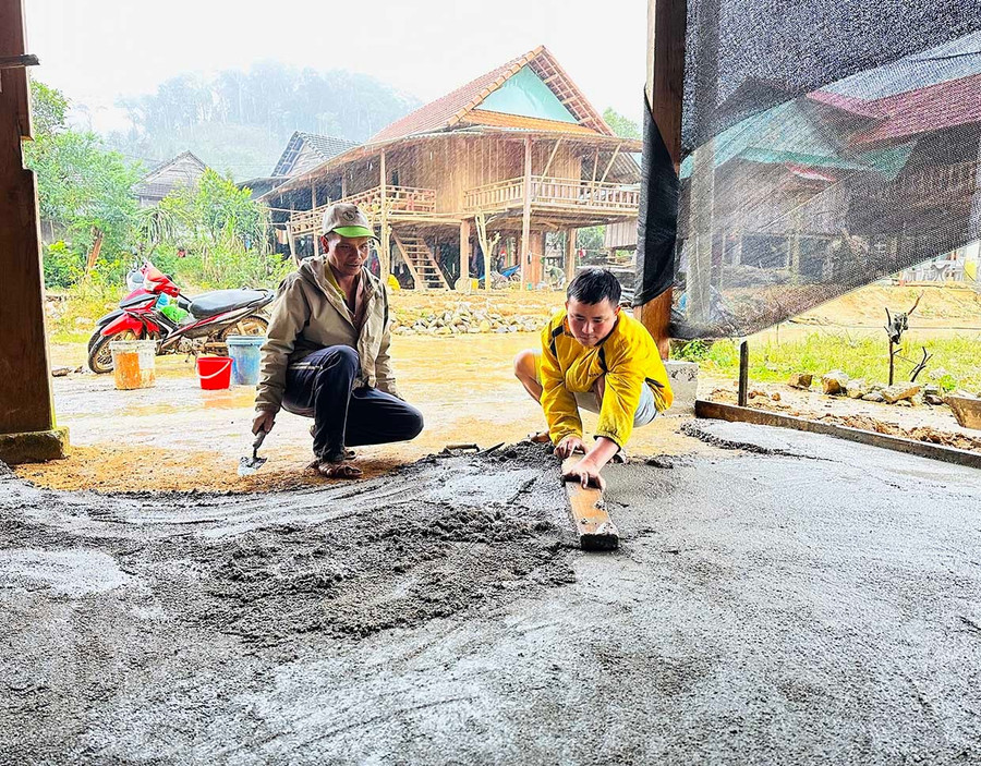 Anh Đinh Văn Típ (bìa trái, khu tái định cư thôn 2, xã An Toàn) cùng hàng xóm đổ bê tông sân dẫn vào ngôi nhà sàn mới xây. Ảnh: D.Đ