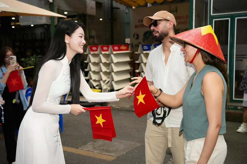 Du khách quốc tế được tặng cờ Tổ quốc tại Đường sách Thành phố Hồ Chí Minh. Ảnh: CTV/Vietnam+ maimai.jpg