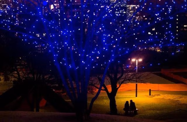 Cặp đôi ngồi trong công viên trung tâm Tokyo dưới ánh đèn của đêm Giáng sinh. ẢNH: REUTERS
